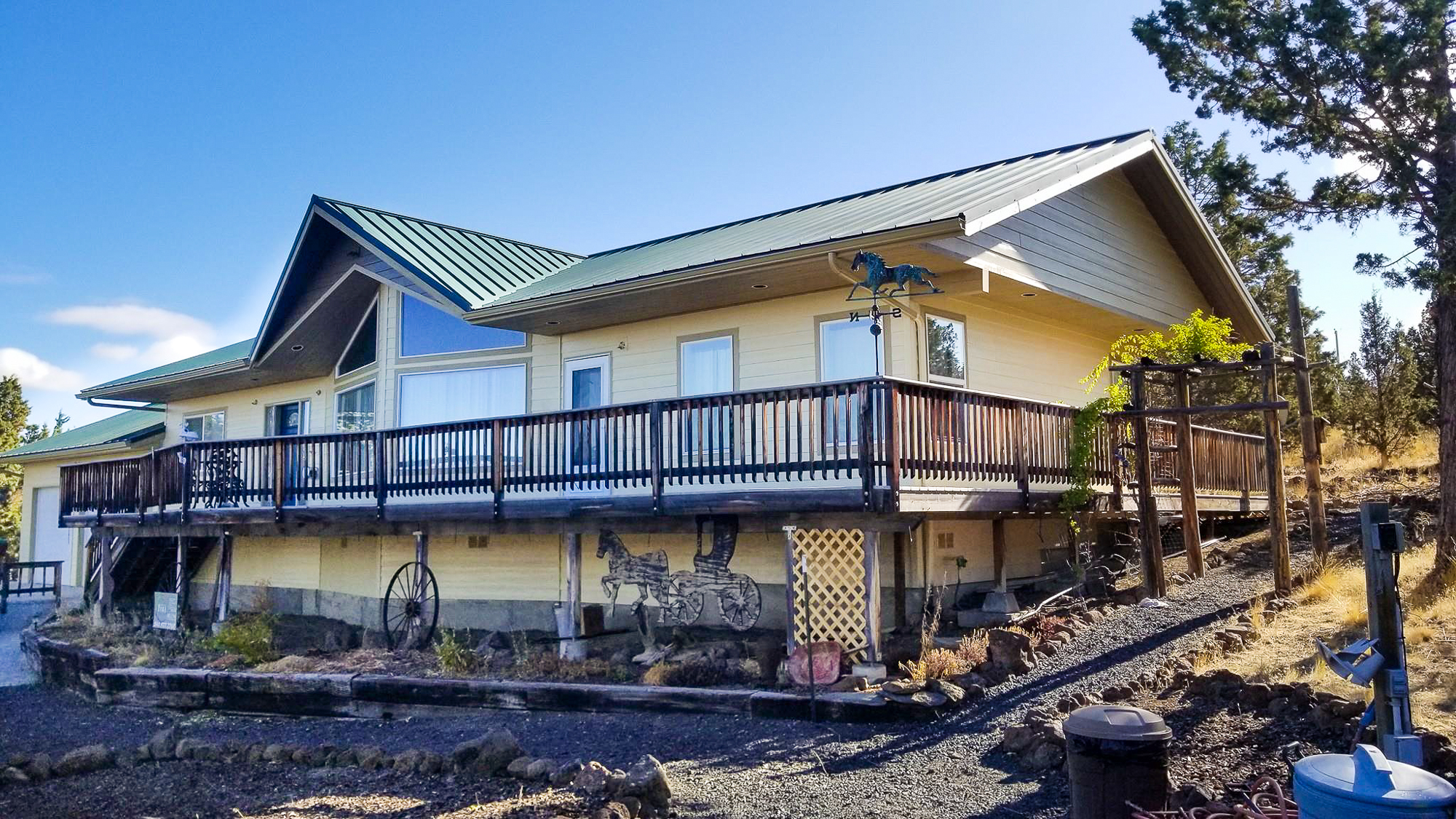 Finished exterior repaint, large cabin-style home with cream siding and a dark green metal roof