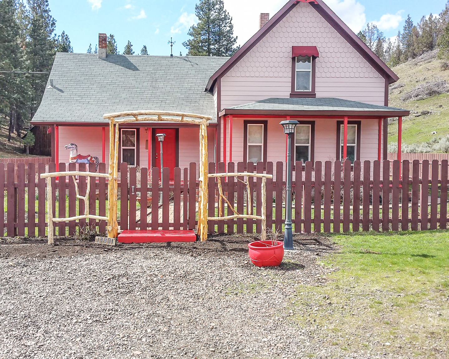Finished exterior repaint of a historic Victorian-style farmhouse, pink body with burgundy trim and a picket fence