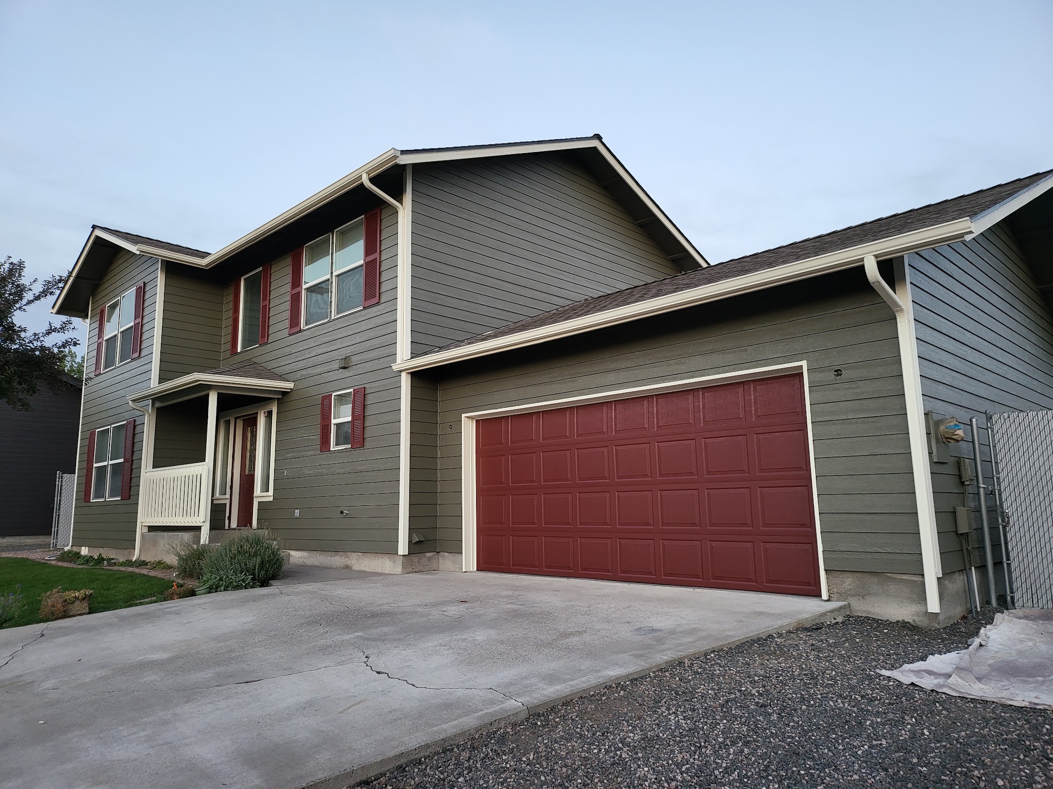 Finished exterior repaint, olive-gray two-story home with a deep red garage door and window trim