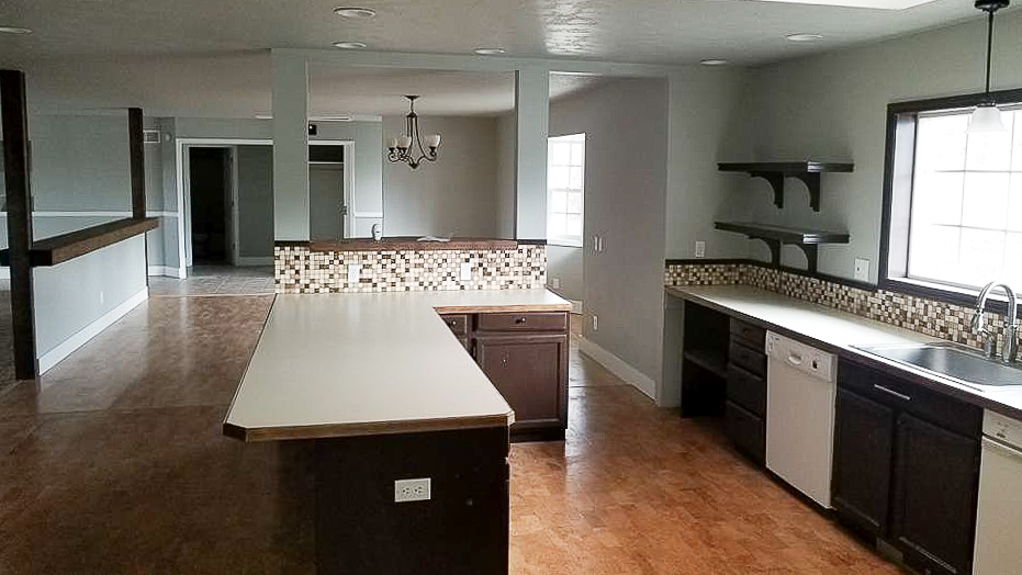 Finished interior kitchen repaint, light gray walls with wood cabinetry and a tiled backsplash